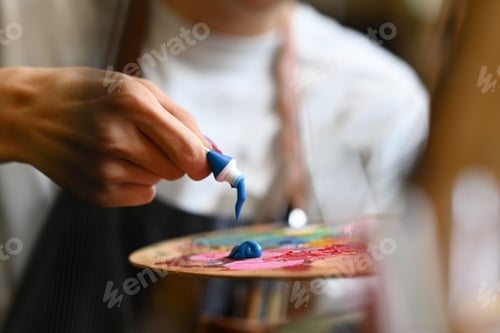 Preview: Cropped image of male artist holding painting brush and mixing color oil painting on palette.