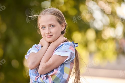 Preview: Young caucasian girl with blonde hair smiling outdoors in the sunlight