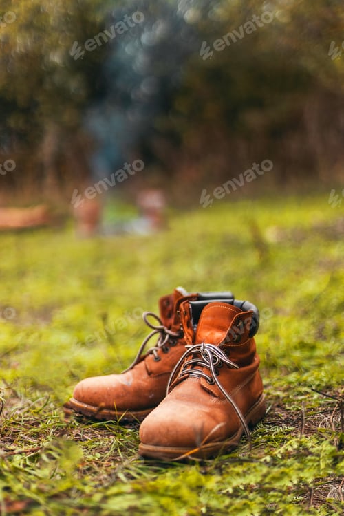 Preview: Close up of hiking boots drying out next to campfire during sunset