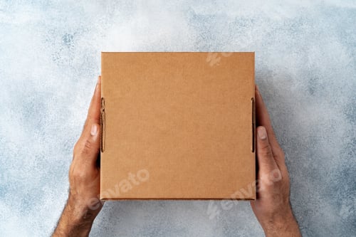 Preview: Parcel cardboard box in a man hands on a gray table background