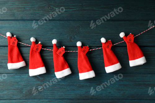 Preview: Twine with Santa Claus hats with red houses on wooden background