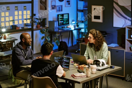 Preview: Multiethnic Young Adults Collaborating on Software Development Project at Night