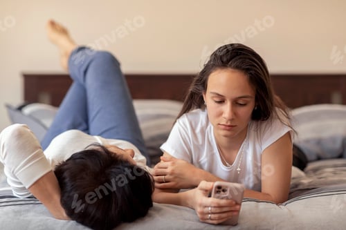 Preview: Woman Looking At Phone While Lying on Bed