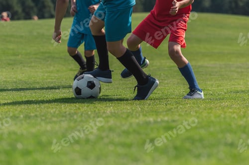 Preview: cropped view of three kids playing football on grass