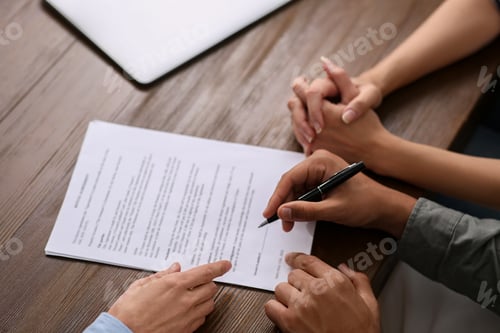 Preview: Notary helping couple with paperwork at wooden table, closeup