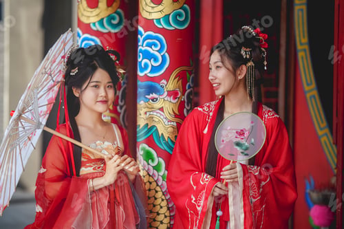 Preview: Two women dressed in traditional red attire with accessories in a cultural setting