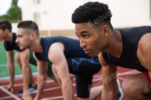 Preview: Multiethnic athlete group ready to run. Focus on african man.