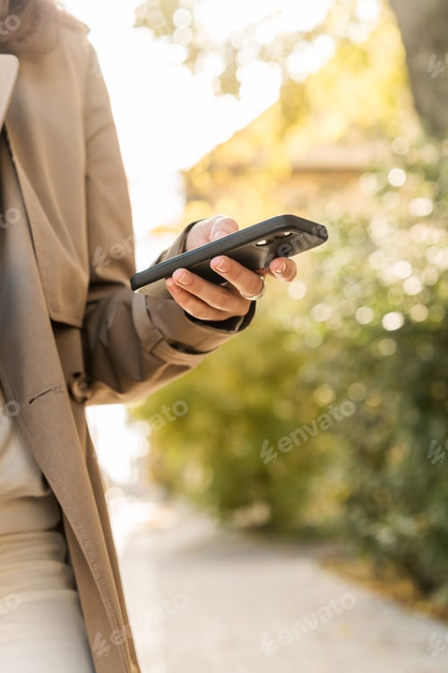 Preview: Cropped shot of female using smartphone in the city. Making online purchases with mobile phone