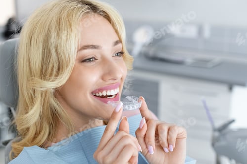 Preview: Young attractive woman holding invisible braces or trainer