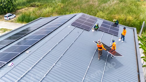 Preview: Workers installing solar panels on a metal roof, aerial view of renewable energy project