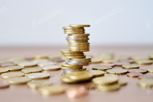 Preview: Pile of coins on a wooden table with shallow depth of field