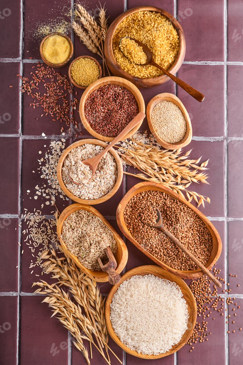 Preview: White, brown and red rice, buckwheat, millet, corn groats, quinoa and bulgur in wooden bowls on a br