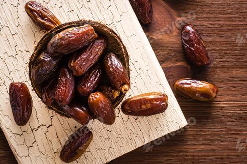 Preview: Sweet dried dates fruit in small wooden bowl on a shabby board. Top view