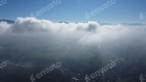 Preview: Drone view of a town covered in thick fog under the sunlight and a blue sky