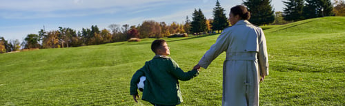 Preview: african american boy holding football, walking with mom on green field, holding hands, fall, banner