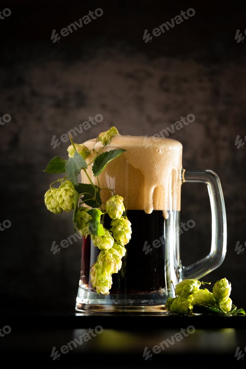 Preview: Glass of dark beer with hops around on a dark background