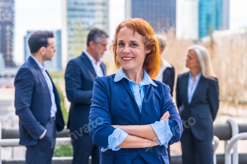 Preview: Confident Redhead Executive with Business Team in Modern Urban Landscape
