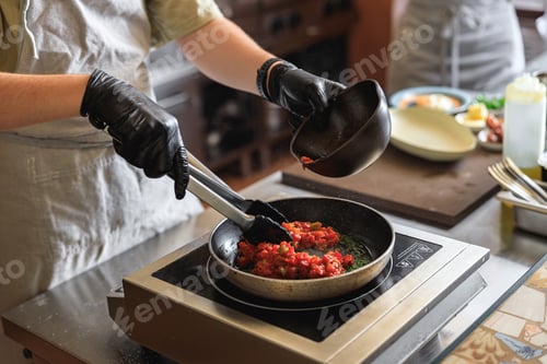 Preview: Close up of chef in uniform is cooking dish on frying pan for client order