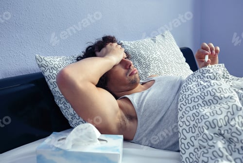 Preview: Sick man looking temperature in thermometer on bed