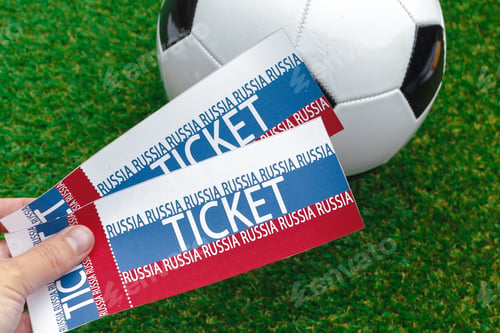 Preview: Key soccer tickets held in hand against a vibrant green grass background