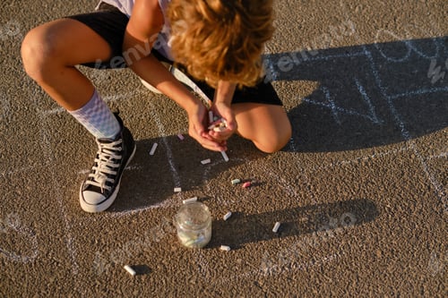 Preview: Boy with handful of chalks on asphalt road