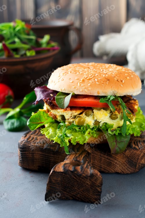 Preview: Vegetarian burger with scrambled eggs and peas, slice of tomato, fresh salad, arugula on old wooden