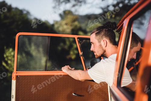 Preview: A young man getting out of a car on a roadtrip through countryside.