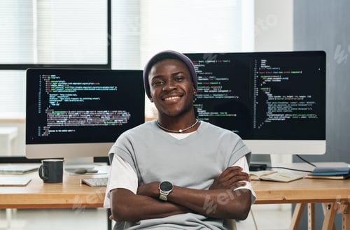 Preview: Happy young successful IT engineer in casualwear sitting by workplace