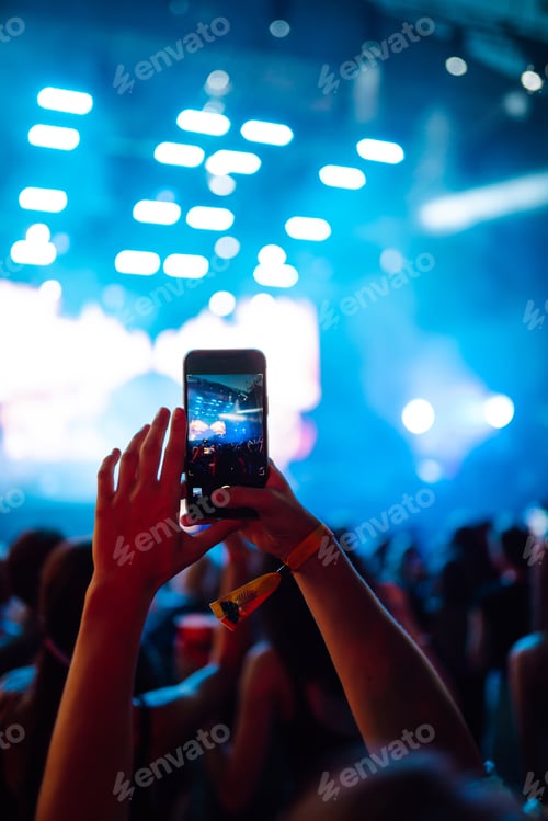 Preview: Hand with a phone records live music festival. People taking photographs with smart phone.