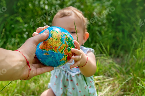 Preview: The child holds the globe in his hands. Selective focus.