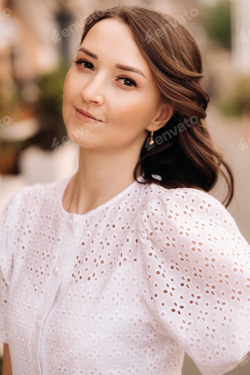 Preview: A beautiful woman in a white dress at sunset in the city. Evening street photography