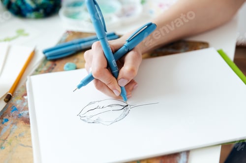 Preview: Woman artist hands drawing with gel ink pen in sketchbook