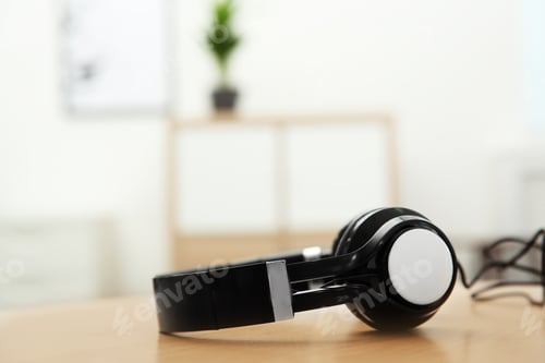 Preview: Stylish headphones on table indoors. Space for text