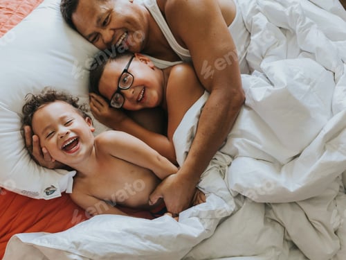 Preview: Father and Two Children Lying in Bed Laughing
