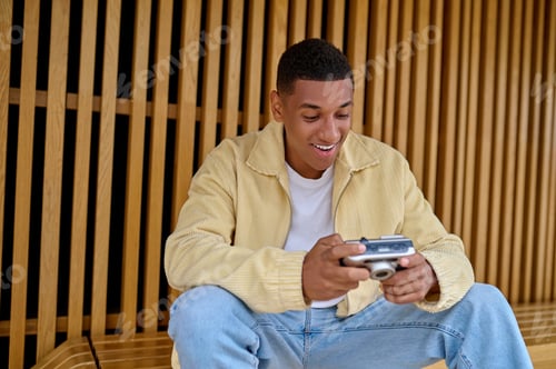 Preview: Male photographer sitting and holding camera in hands
