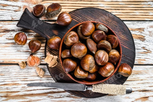 Preview: Bowl with chestnuts on a wooden table. White background. Top view
