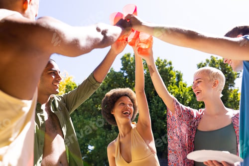 Preview: Happy diverse group of friends making a toast in garden