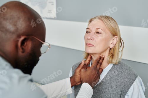 Preview: Mature blond female patient having checkup of her thyroid by endocrinologist