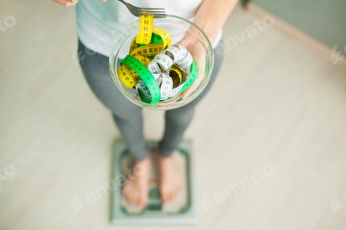 Preview: Diet and Weight Loss. Woman holds bowl and fork with measuring tape