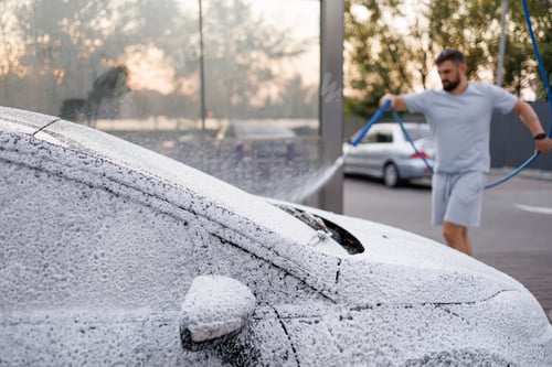 Preview: The hood and windshield of the car are covered with foam, the man in the background