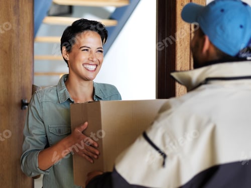 Preview: Shot of a smiling young woman standing at her front door receiving a package from a courier
