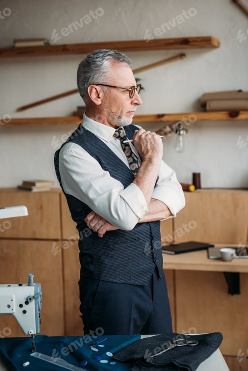 Preview: pensive handsome tailor looking away at sewing workshop