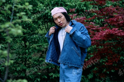 Preview: Stylish young man showcases denim fashion in a vibrant park setting