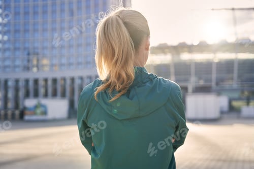Preview: Back view of middle aged woman in sportswear standing outdoors, ready for morning workout