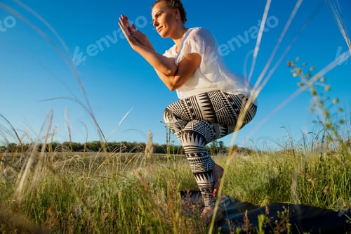 Preview: Girl doing yoga on a beautiful green meadow