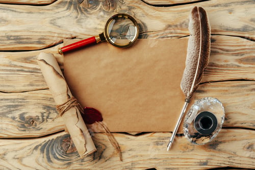 Preview: Old paper on brown wood background with feather