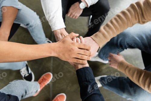 Preview: Top view of multiethnic group of people with alcohol addiction holding hands together in rehab