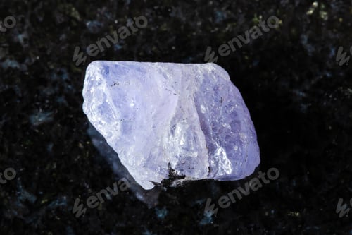 Preview: sample of rough tanzanite mineral on black granite