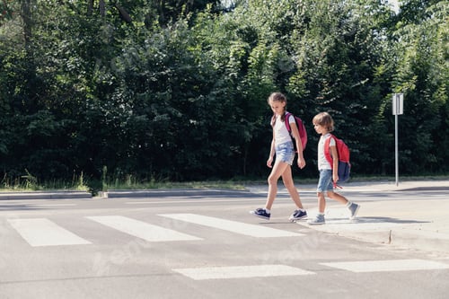 Preview: Girl and boy with backpacks walking on pedestrian crossing from