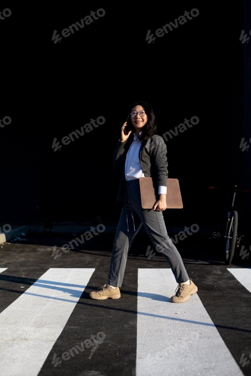 Preview: young Asian business woman goes and uses mobile phone in her hands a urban background a modern offic